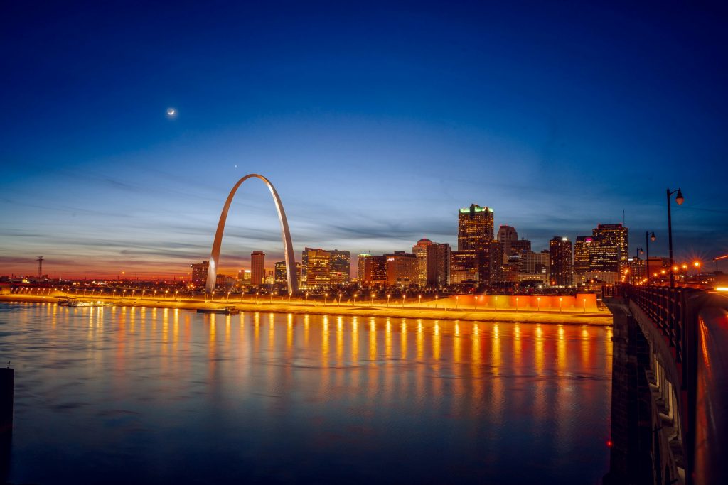 A picture of the St. Louis arch at night from across a river.