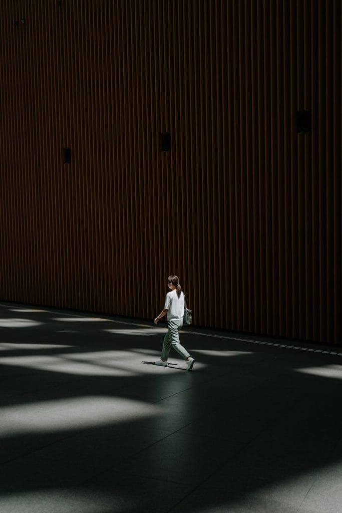 A person walks in a sunlit modern hallway.